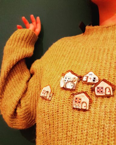 Suéter beige con broches de casas dibujadas en la parte frontal.