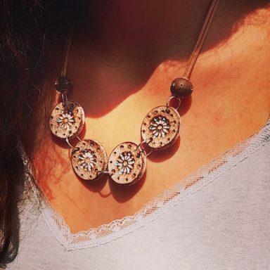 Collar de cuentas en tonos naturales con diseño circular y detalles en relieve.