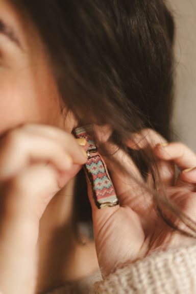 Una persona coloca un pendiente de diseño colorido en su oreja.